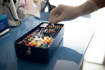 Closeup of hand placing drills assortment on table in dental clinic.
