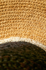 Fragment of a straw hat. Sand-colored field and black top. Closeup. Copy space. Summer concept