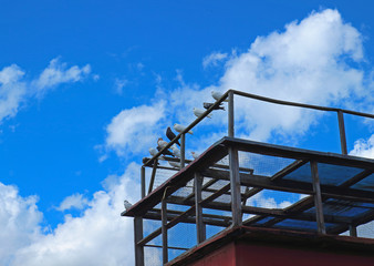 Domestic doves in dovecote against the blue sky with clouds. Pigeons sitting on old latticed...