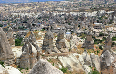 Fototapeta premium The town Göreme with rock houses in front of the spectacularly coloured valleys nearby. Cappadocia, Central Anatolia, Turkey.