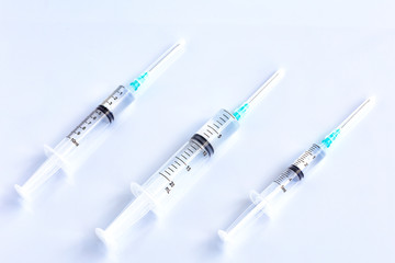 Several different syringes on a light smooth table, ready to use.