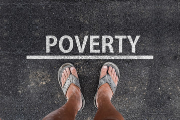 poverty. man with dirty feet in slippers is standing on asphalt next to line and word poverty - obrazy, fototapety, plakaty