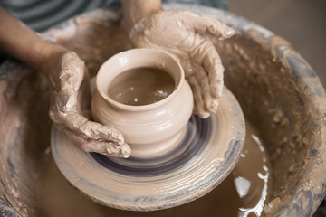 Fototapeta na wymiar Art therapy. Woman's hands make a pot of clay on a potter's wheel. Close-up