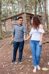 Fototapeta premium Couple walking holding hands smiling in the forest- full body