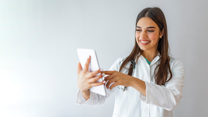 Healthcare, technology and medicine concept - smiling female doctor with stethoscope and tablet pc computer. Young happy medical worker using tablet computer.