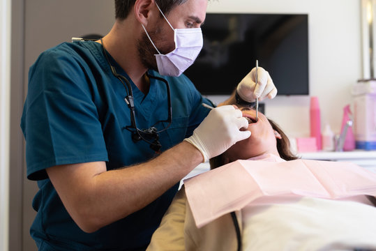Close up of dentist with a mask examining a patient in dental clinic.