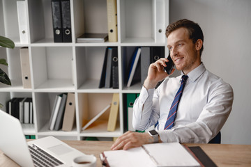 Relaxed man talking on the phone at work and smiling