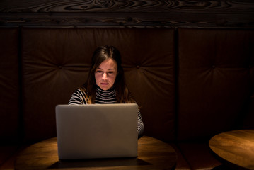 Woman working on laptop in dimly lit lounge