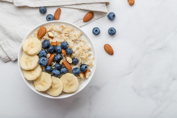 Oatmeal porridge with blueberries, almonds and banana on marble table