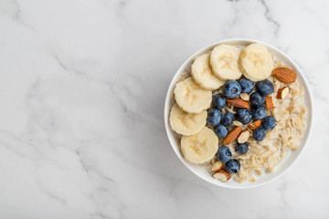 Oatmeal porridge with blueberries, almonds and banana on marble table