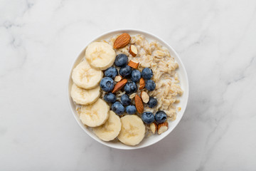 Oatmeal porridge with blueberries, almonds and banana on marble table