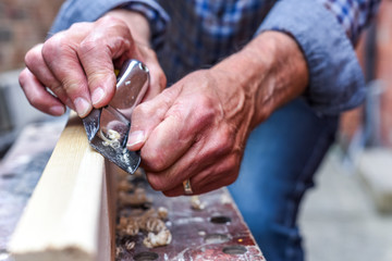 Close up of mans hands working with a plane on wooden plank