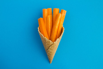 Ice cream cone with sliced carrots  in the center of the blue  background.Top view.Copy space.