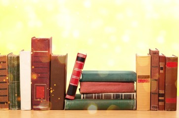 Collection of old books on wooden table on library background