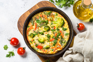 Frittata with vegetables on white stone table.