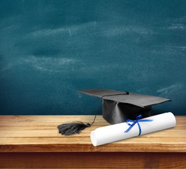 Graduation mortarboard on book on  background