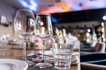Wine glasses in the foreground. Wedding Banquet or gala dinner. The chairs and table for guests, served with cutlery and crockery.