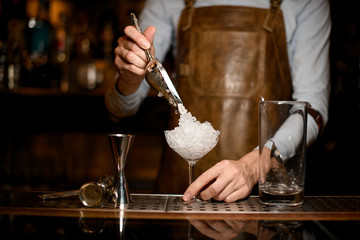 Male bartender putting crushed ice to the glass