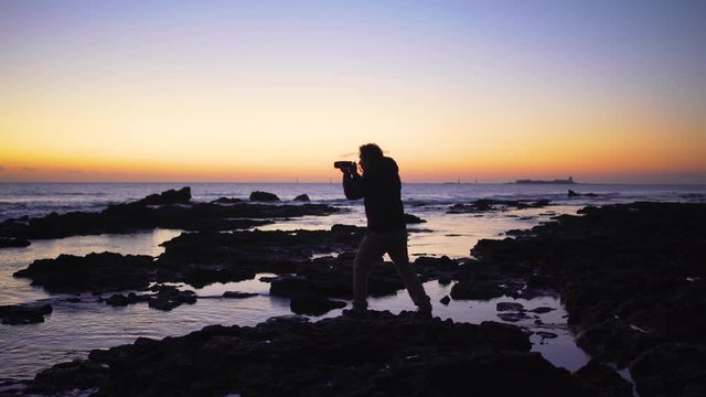 A photographer silhouette taking photos in the sea at sunset	