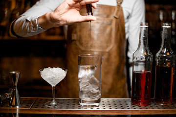 Male bartender adding an essence from the little glass bottle