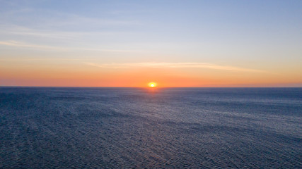 Fototapeta na wymiar Sunset over the sea in clear weather, view from above. Seascape with evening sun and deep blue sea.