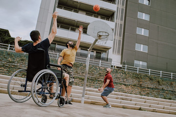 a man in wheelchair plays basket with friends