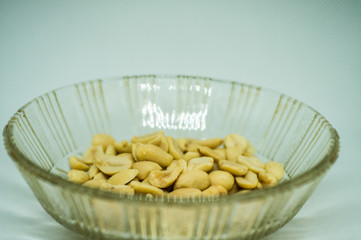 Peeled peanuts without husk in a glass plate on a white background close-up