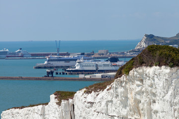 Port of Dover with ferry ships docked in passengers terminal and view over white cliffs, on a sunny summer day, south east England .