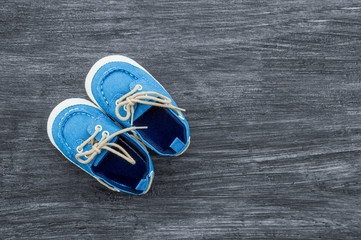 Baby shoes on a wooden background with space for text. Top view
