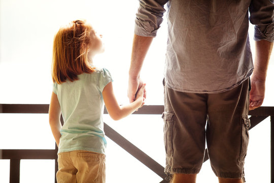 Father and daughter (6-7) holding hands on porch