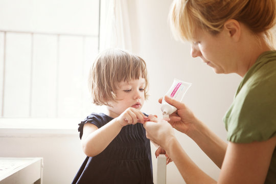 Mother applying toothpaste on daughter's (2-5 months) toothbrush