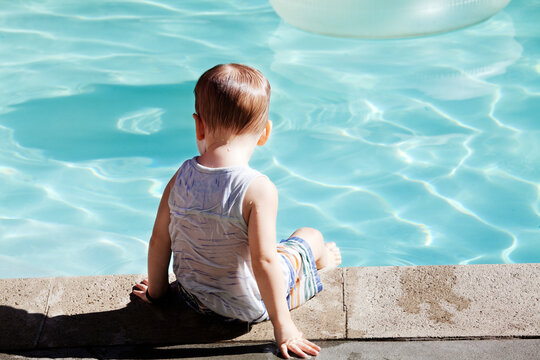 Rear view of boy sitting at poolside