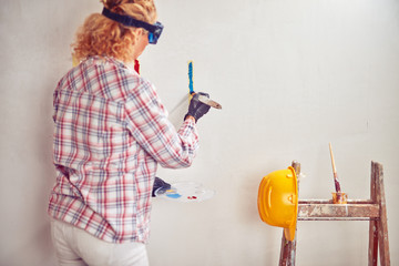 Working woman plastering / painting walls inside the house.