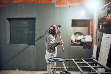 Painter painting walls with a extender roller indoors.