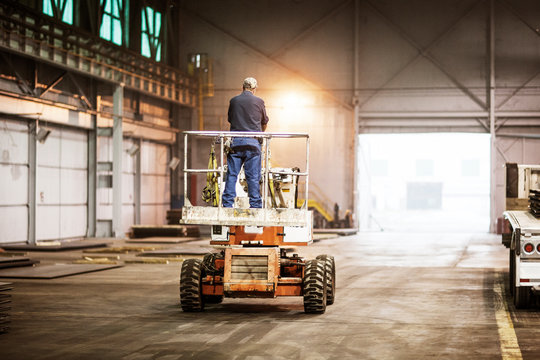 Rear view of man working on cherry picker