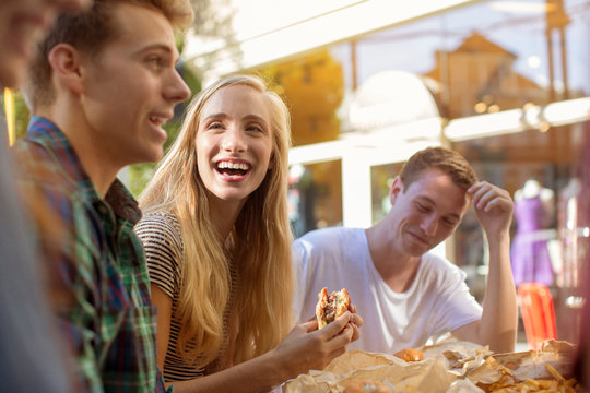 Teenage girl (16-17) laughing with friends at restaurant