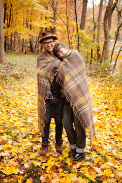 Couple wrapped in blanket in autumn forest