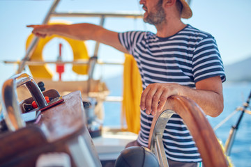 Sailor using wheel to steer rudder on a sailing boat. © astrosystem