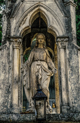 Fototapeta na wymiar Marble statue and an ancient abandoned Gothic cemetery