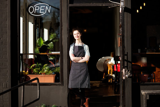 Portrait of smiling waitress standing at doorway