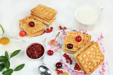 Crispy waffles with berries on a sunny table. Morning breakfast with waffles and milk, top view