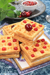 Crispy waffles with berries on a sunny table. Morning breakfast with waffles, currants and milk on...