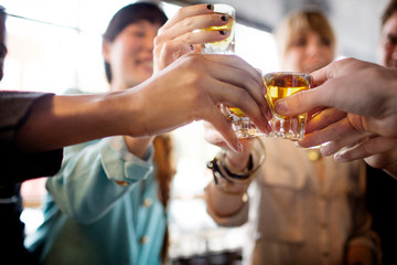 Close up of friends toasting shot glasses