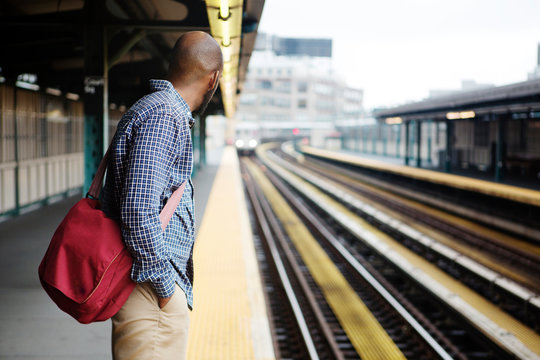 Young man waiting for train arriving on platform