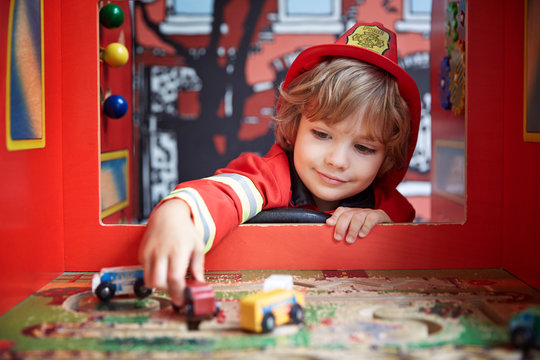 Boy in firefighter costume playing with toy car