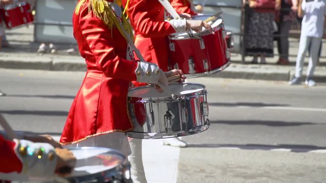 Street performance of festive march of drummers girls in red costumes on city street