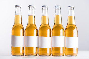 five beer bottles with blank white labels isolated on grey
