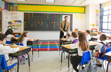 Grade school teacher speaking to students (8-9, 10-11) in class © Cavan for Adobe