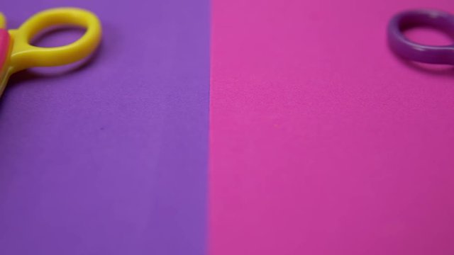 Close up of a variety of wavy blade scissors for scrapbooking on colorful paper moves from right to left. Abstract minimal background.