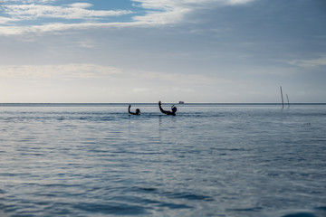 two people in the distance waving to camera, snorkeling